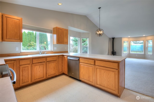 kitchen with pendant lighting, a wood stove, sink, vaulted ceiling, and appliances with stainless steel finishes