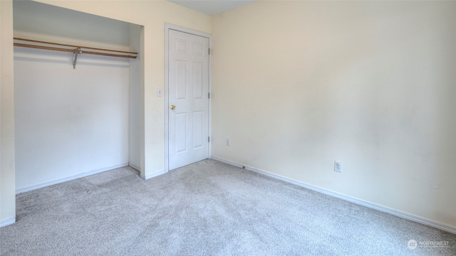 unfurnished bedroom featuring light carpet and a closet