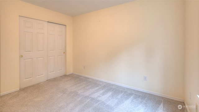 unfurnished bedroom featuring light colored carpet and a closet