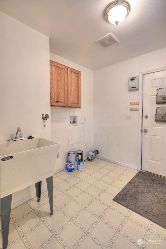 clothes washing area with washer hookup and cabinets