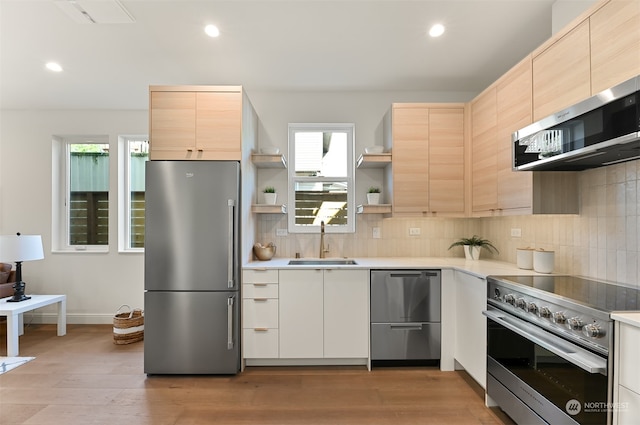 kitchen featuring high end appliances, sink, decorative backsplash, and light brown cabinetry