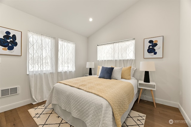 bedroom with vaulted ceiling, dark hardwood / wood-style flooring, and multiple windows