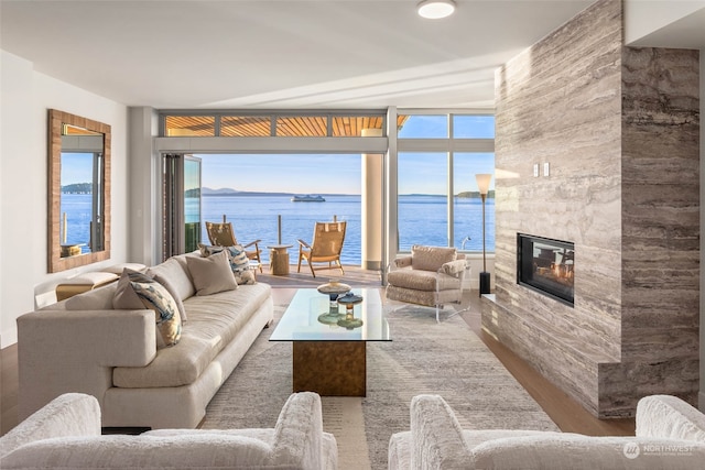 living room featuring a large fireplace, a water view, and wood-type flooring