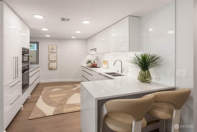 1250 Alki Ave SW Phg, Phg, Seattle, WA 98116 - kitchen featuring modern cabinets, a sink, white cabinetry, light wood finished floors, and recessed lighting