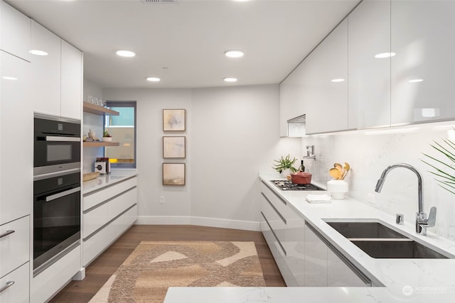 kitchen featuring white cabinets, sink, decorative backsplash, dark hardwood / wood-style flooring, and light stone counters