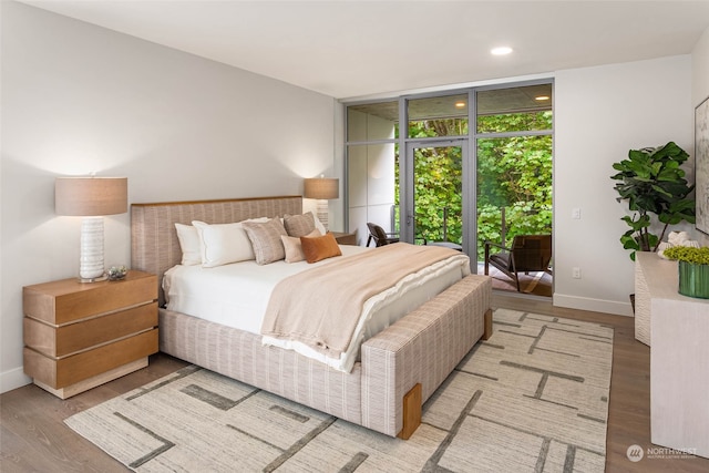 bedroom with access to exterior, light hardwood / wood-style floors, and floor to ceiling windows