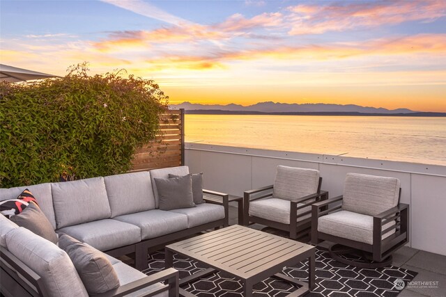 patio terrace at dusk featuring an outdoor living space and a water and mountain view