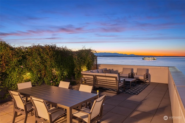 patio terrace at dusk with an outdoor hangout area and a water and mountain view