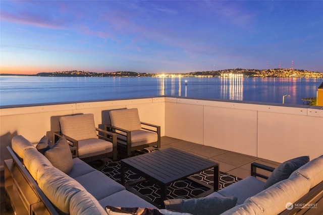 patio terrace at dusk featuring a water view and an outdoor hangout area