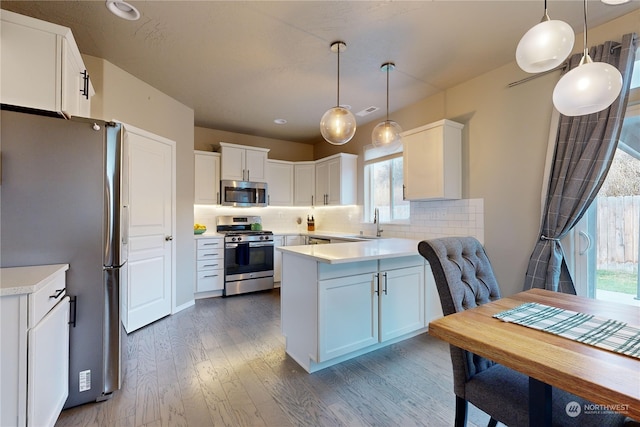 kitchen featuring white cabinetry, hanging light fixtures, and appliances with stainless steel finishes