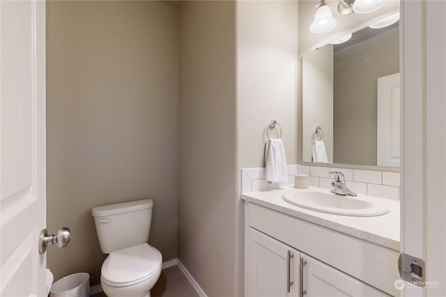 bathroom with vanity, toilet, and backsplash