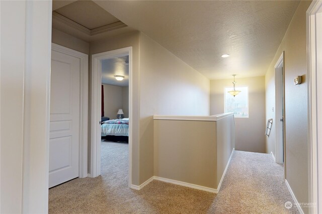 hallway with light colored carpet and a textured ceiling