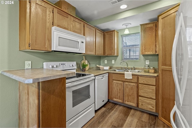 kitchen with kitchen peninsula, dark hardwood / wood-style flooring, sink, and white appliances