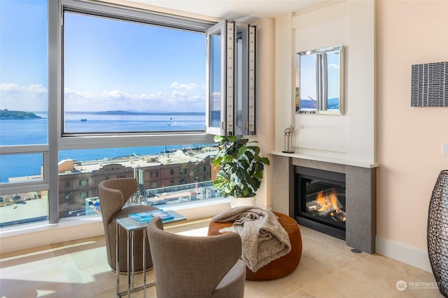 living area with a water view, a healthy amount of sunlight, and light tile patterned floors