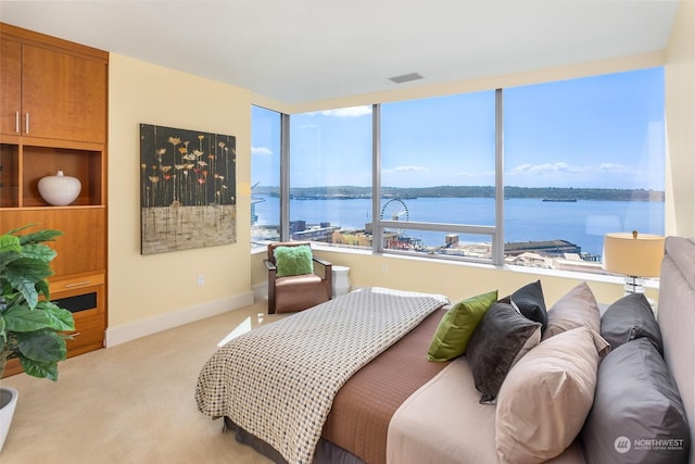 bedroom featuring light carpet and a water view