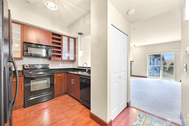 kitchen with pendant lighting, sink, light hardwood / wood-style flooring, and black appliances