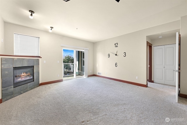 unfurnished living room with light carpet and a tiled fireplace