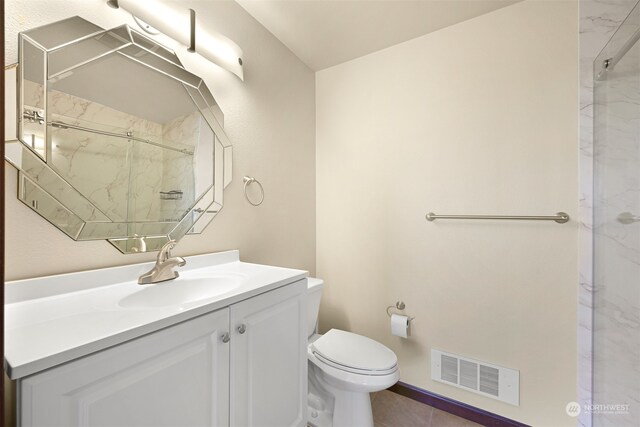 bathroom with tile patterned flooring, vanity, toilet, and a shower with shower door