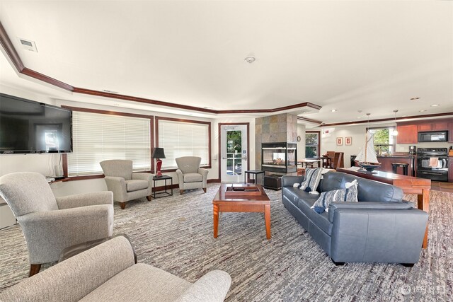 living room with a tile fireplace and ornamental molding