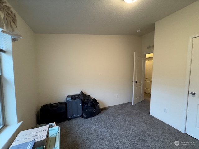 interior space featuring dark colored carpet and a textured ceiling