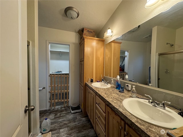 bathroom with a textured ceiling, vanity, wood-type flooring, and a shower with door