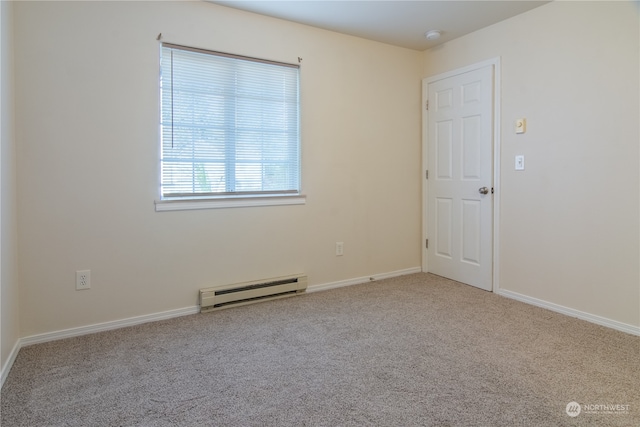 carpeted spare room featuring a baseboard heating unit