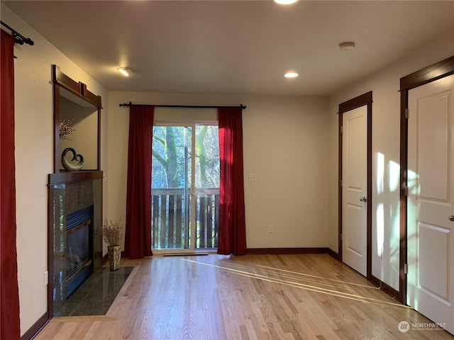 unfurnished living room with a tile fireplace and light hardwood / wood-style flooring