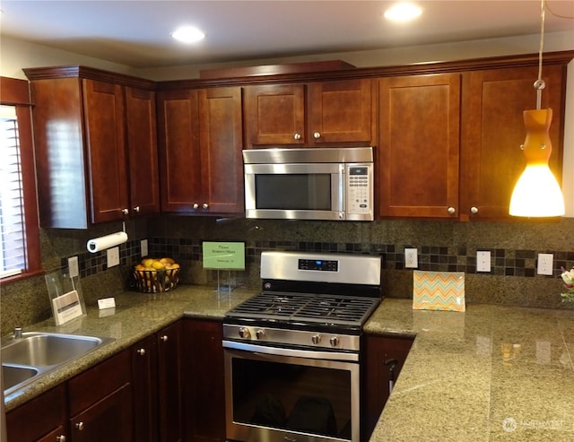 kitchen featuring stone countertops, stainless steel appliances, a wealth of natural light, and sink