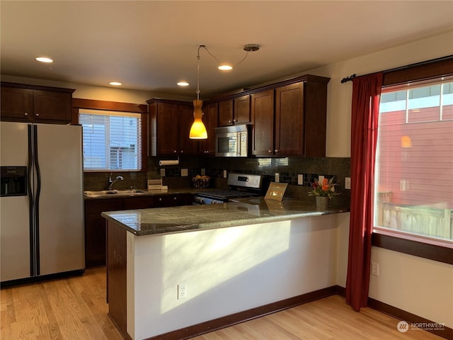 kitchen featuring pendant lighting, light hardwood / wood-style floors, kitchen peninsula, and appliances with stainless steel finishes