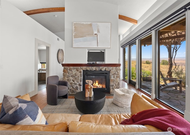 living room with a stone fireplace, lofted ceiling, and light wood-type flooring