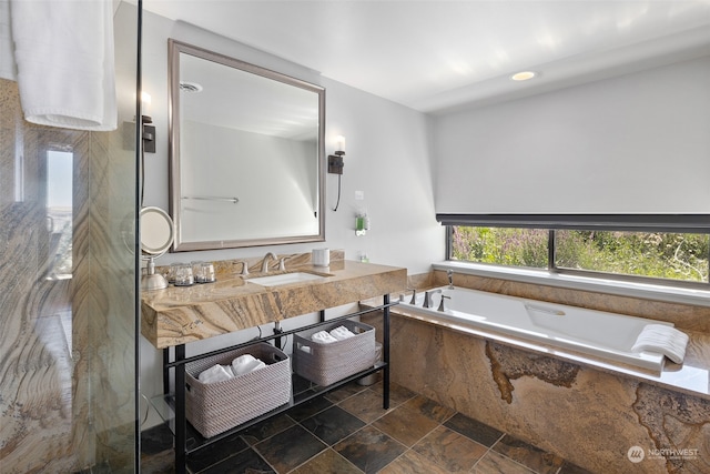 bathroom with a relaxing tiled tub and sink