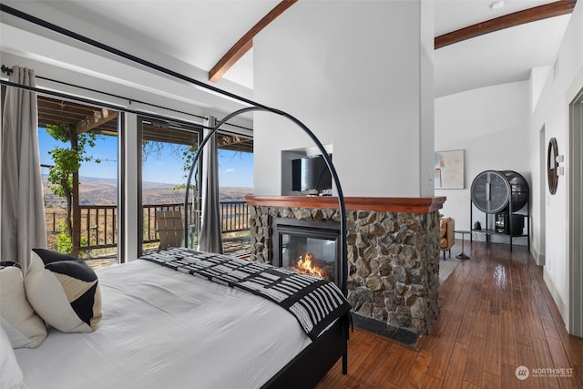 bedroom with a stone fireplace, dark hardwood / wood-style flooring, beamed ceiling, a mountain view, and access to outside