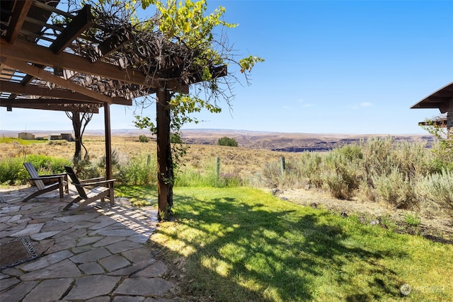 view of yard featuring a rural view, a pergola, and a patio