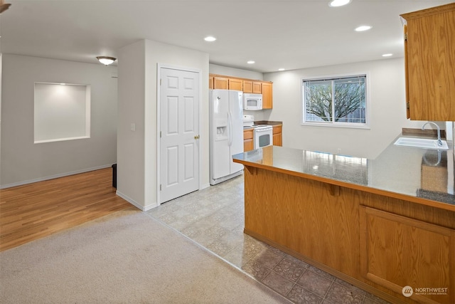 kitchen with kitchen peninsula, white appliances, light hardwood / wood-style floors, and sink