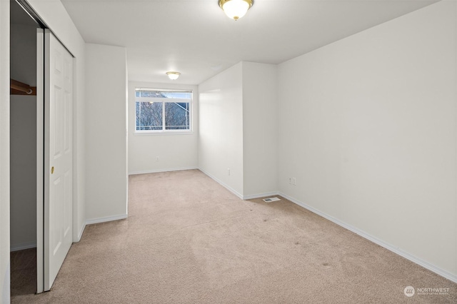 unfurnished bedroom featuring a closet and light colored carpet