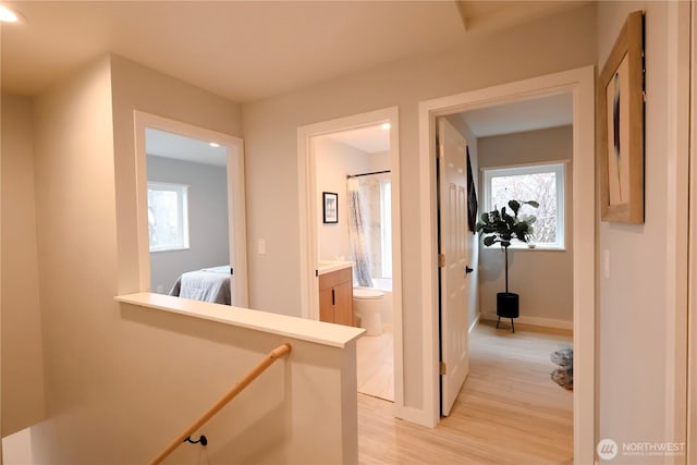 hall featuring light wood-style floors, plenty of natural light, and baseboards