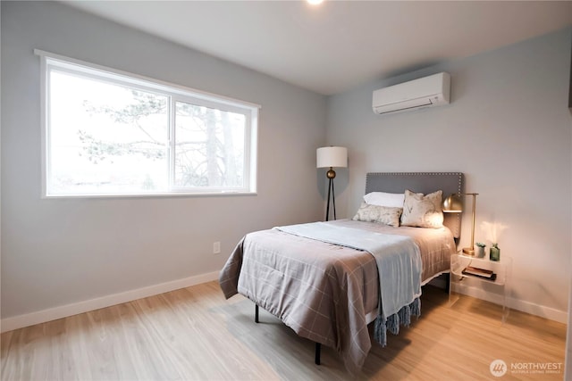 bedroom with a wall mounted AC, wood finished floors, and baseboards