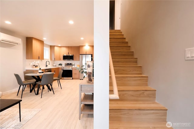 stairway with recessed lighting, a wall unit AC, and wood finished floors