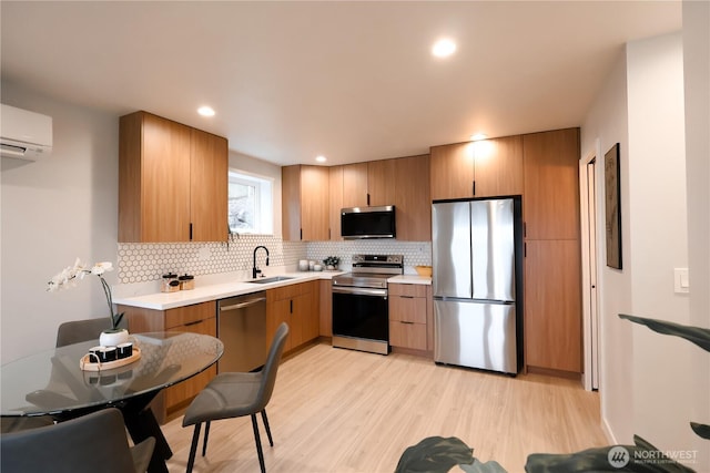 kitchen featuring light wood-style flooring, appliances with stainless steel finishes, a sink, light countertops, and backsplash