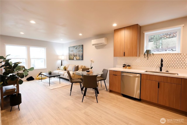 kitchen with dishwasher, a wall unit AC, backsplash, light countertops, and a sink