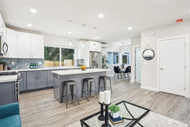 kitchen with appliances with stainless steel finishes, decorative light fixtures, gray cabinetry, and light hardwood / wood-style floors