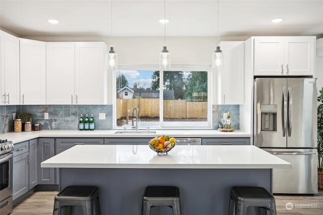 kitchen with a kitchen breakfast bar, gray cabinetry, white cabinetry, and appliances with stainless steel finishes