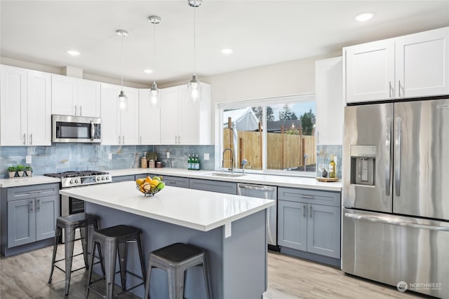 kitchen featuring pendant lighting, white cabinets, a kitchen breakfast bar, sink, and stainless steel appliances