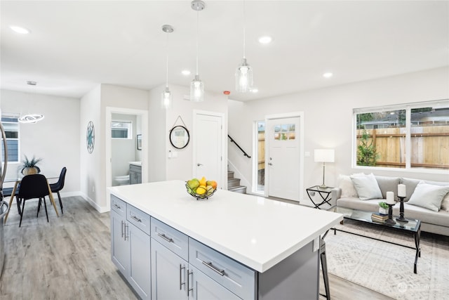 kitchen featuring gray cabinetry, pendant lighting, a center island, light hardwood / wood-style floors, and a breakfast bar area