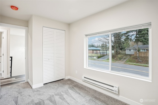 unfurnished bedroom featuring baseboard heating, light carpet, and a closet