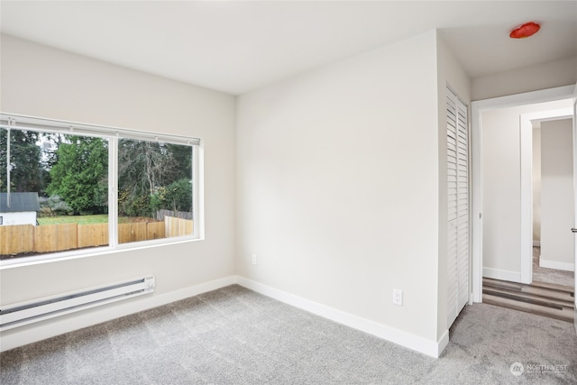 empty room featuring light colored carpet and a baseboard heating unit