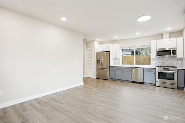 kitchen with gray cabinets, sink, light wood-type flooring, and stainless steel appliances