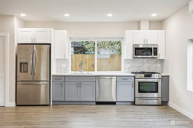 kitchen featuring gray cabinets, white cabinetry, light wood-type flooring, and appliances with stainless steel finishes