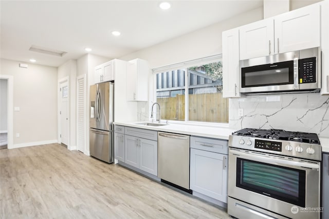 kitchen featuring appliances with stainless steel finishes, light wood-type flooring, white cabinetry, and sink