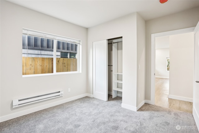 unfurnished bedroom with baseboard heating, a closet, and light colored carpet